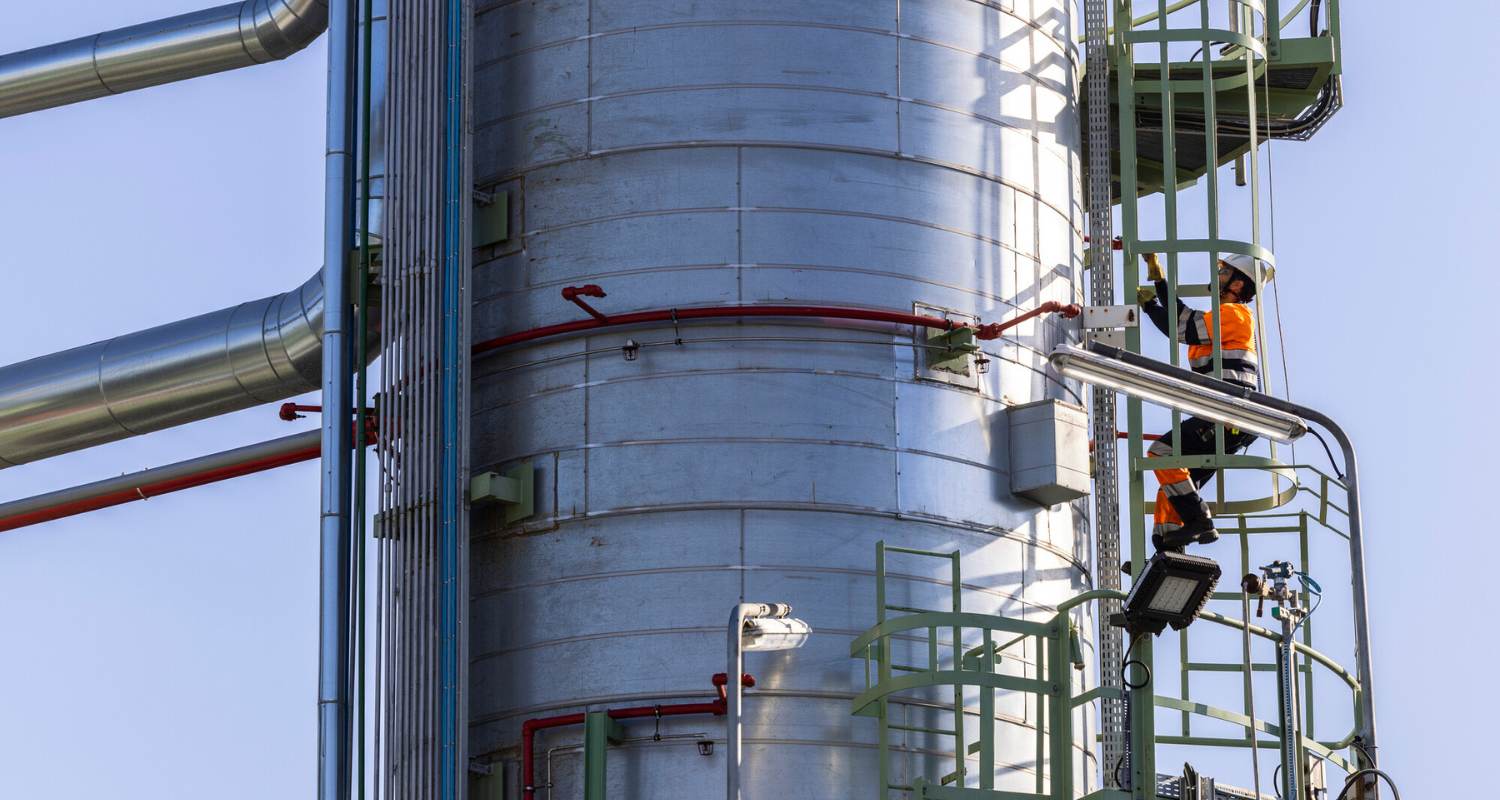 Operario en escalera de chimenea del complejo.