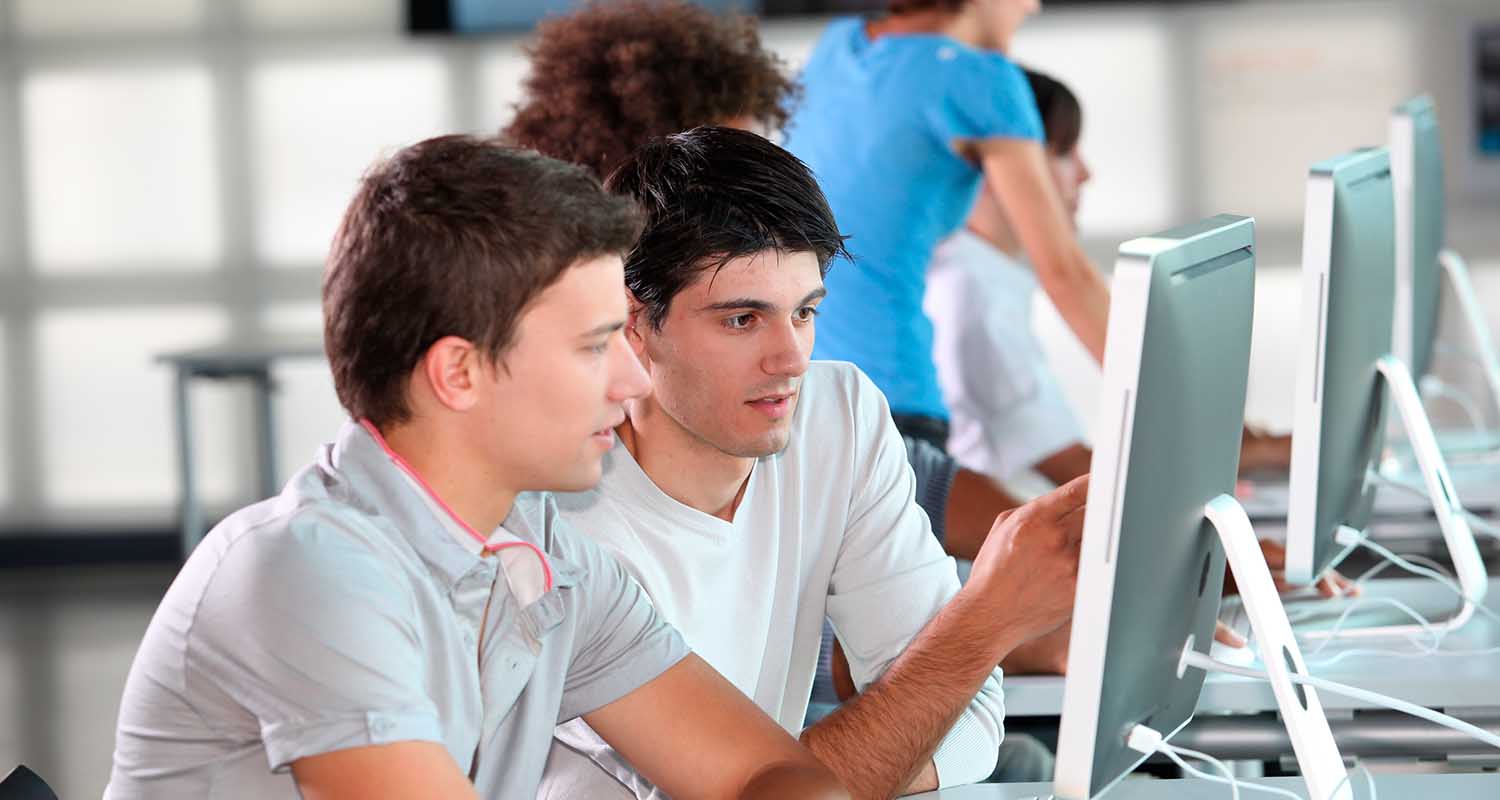 Dos estudiantes sonríen frente al ordenador